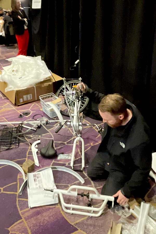 Facilitator assembling a bicycle to be used by presenter on stage