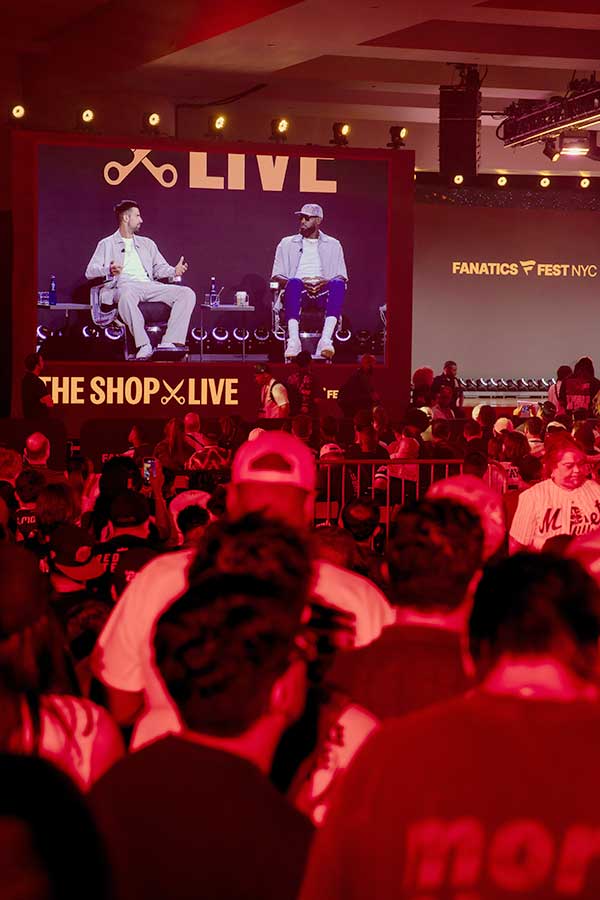 image from crowd of people talking on stage with LED wall behind them