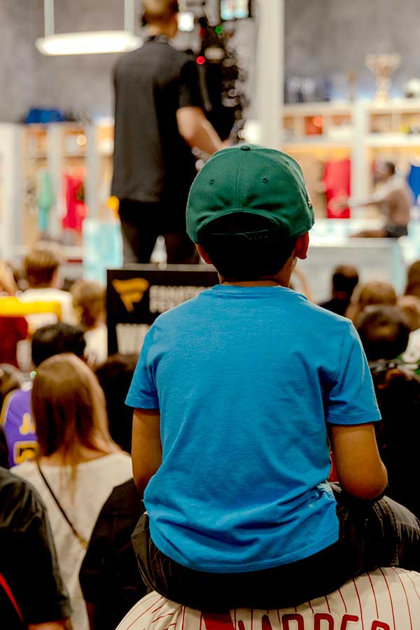 photo of boy on father's shoulders with camera man in background