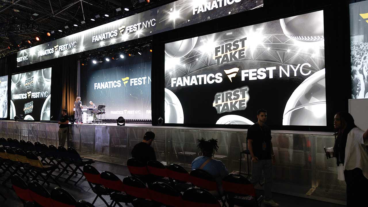Crew preparing the stafe with large screens on both sides of chairs and tables for discussion