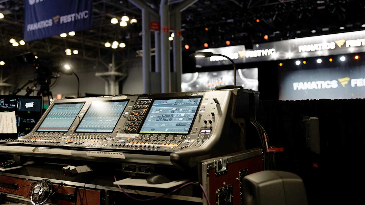 Image of a console that controls audio with the stage in the background 